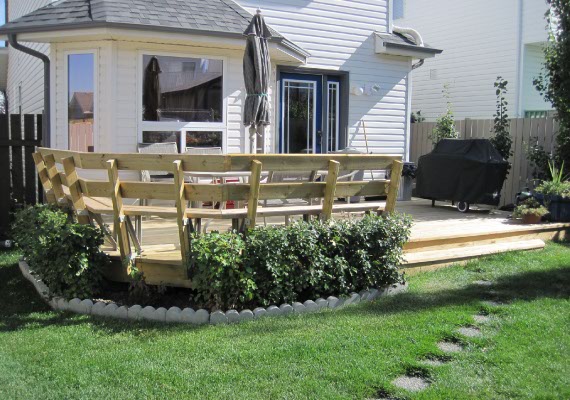 Small wood deck construction with wrap around seating and steps.