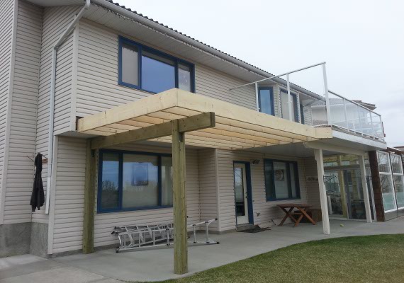 Elevated wood deck extension with glass railings.